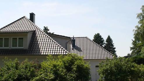 Dachsanierung Blick auf ein großes Haus mit schwarzen Dachziegeln